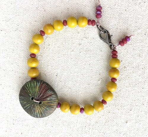 Mustard yellow and mauve bead bracelet with colorful button focal