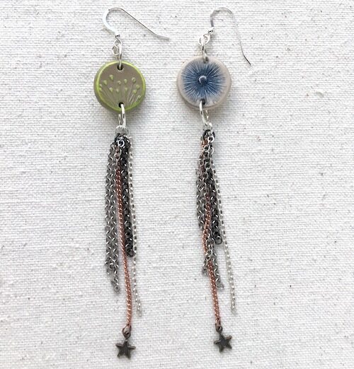 Earrings with mismatched round connectors and long strands of mixed metal chain to form tassels with one star charm at the bottom