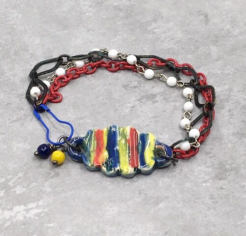 Yellow, red and blue ceramic bracelet bar with white rosary chain, rustic black metal diamond chain and red enamel link chain with blue carabiner pin clasp.