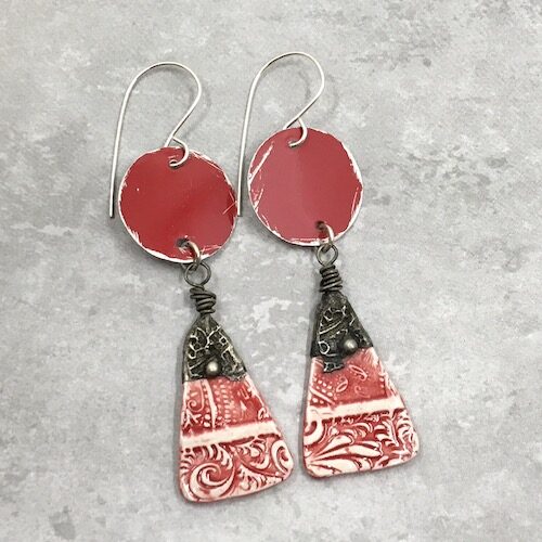 Red and silver earrings with rustic red tin round discs with patterned red and white ceramic headpin drops topped with darkened patterned tinwork.